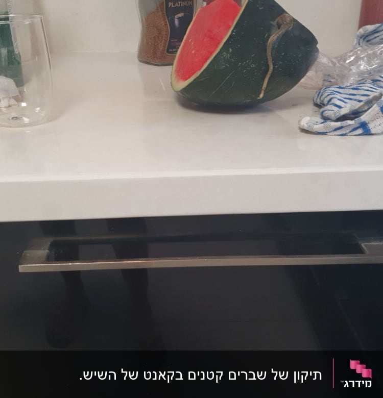 משטח שיש לבן עם כוס זכוכית וחצי אבטיח